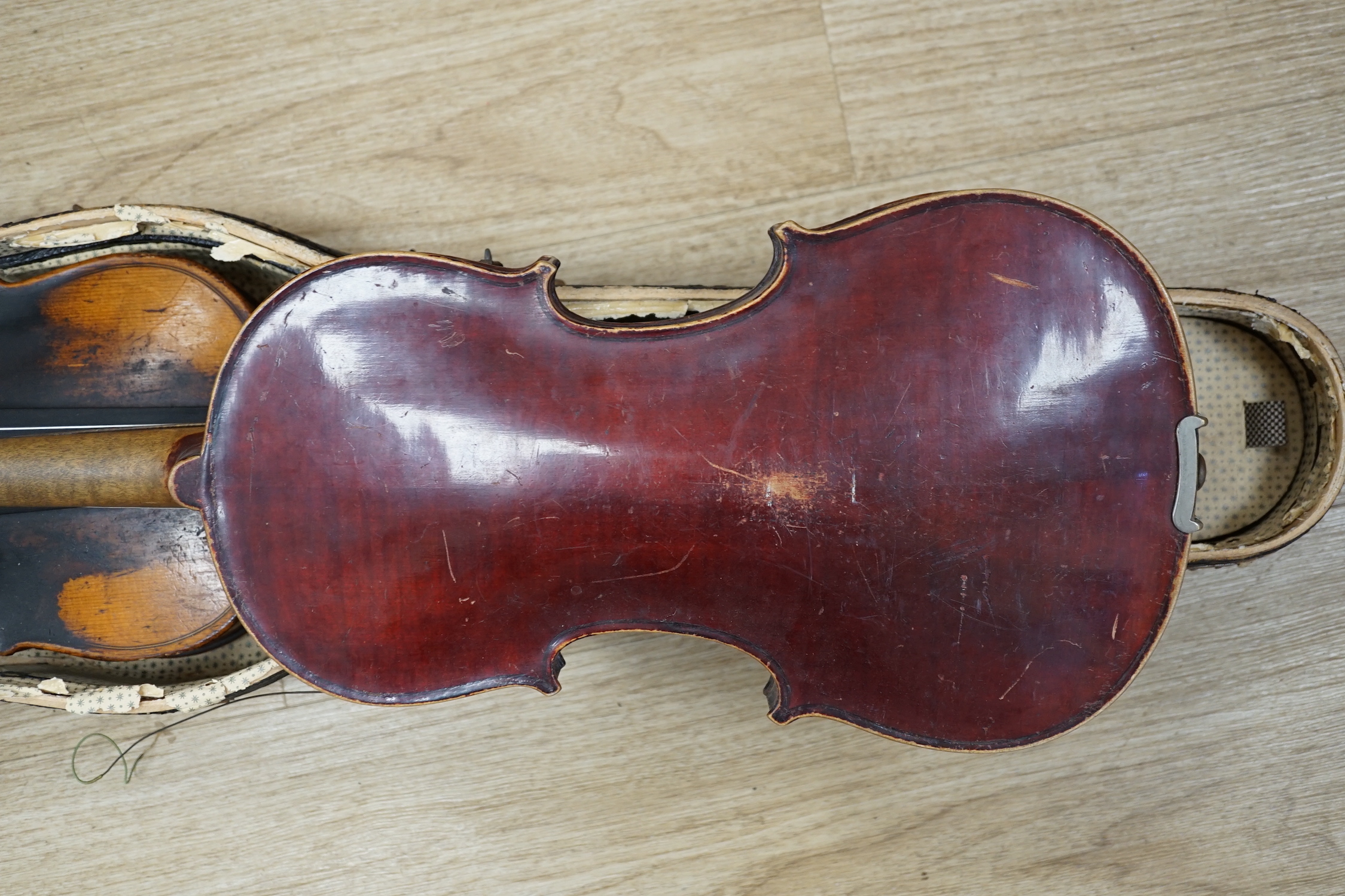 Two early 20th century violins, one in the remains of a case, both for restoration, length of bodies, 35.5cm and 36cm